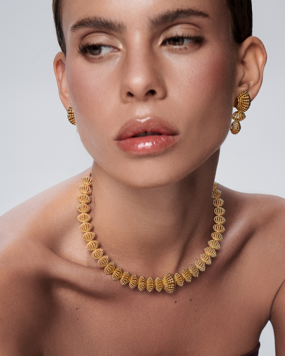 Long gold earrings and necklace designed to frame the face with bold beauty