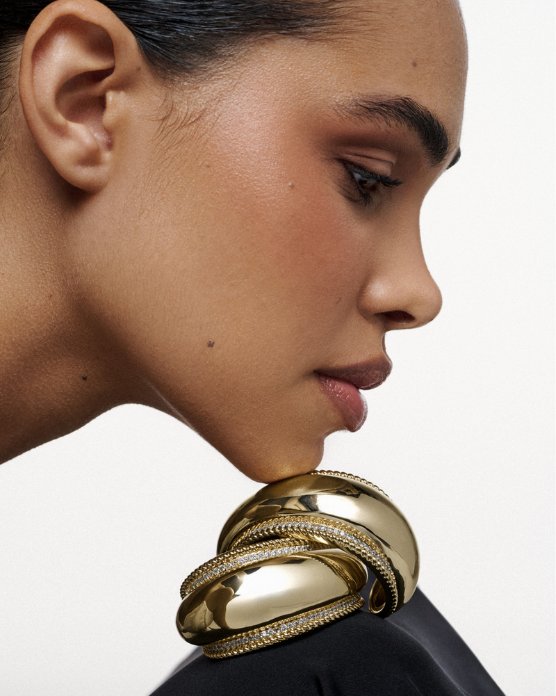 A bold gold cuff with smooth, curved volume, wrapping the wrist with strength and refined elegance lynyer sculptural