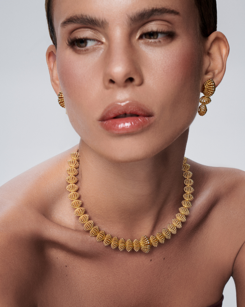 Long gold earrings and necklace designed to frame the face with bold beauty