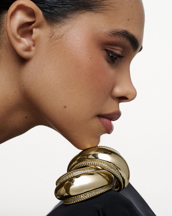 A bold gold cuff with smooth, curved volume, wrapping the wrist with strength and refined elegance lynyer sculptural 