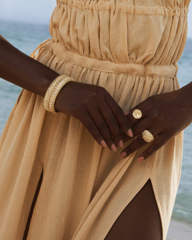 18k brushed gold chunky ring placed on a jewelry dish with soft lighting