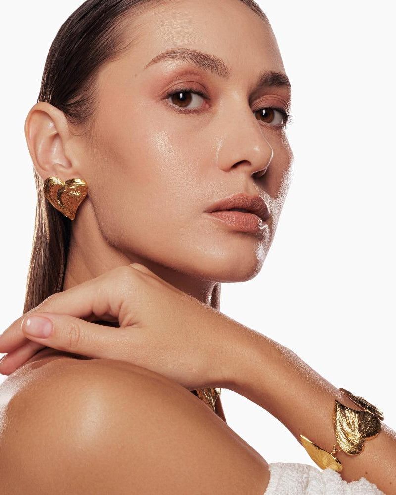 Polished gold heart studs styled with casual outfit